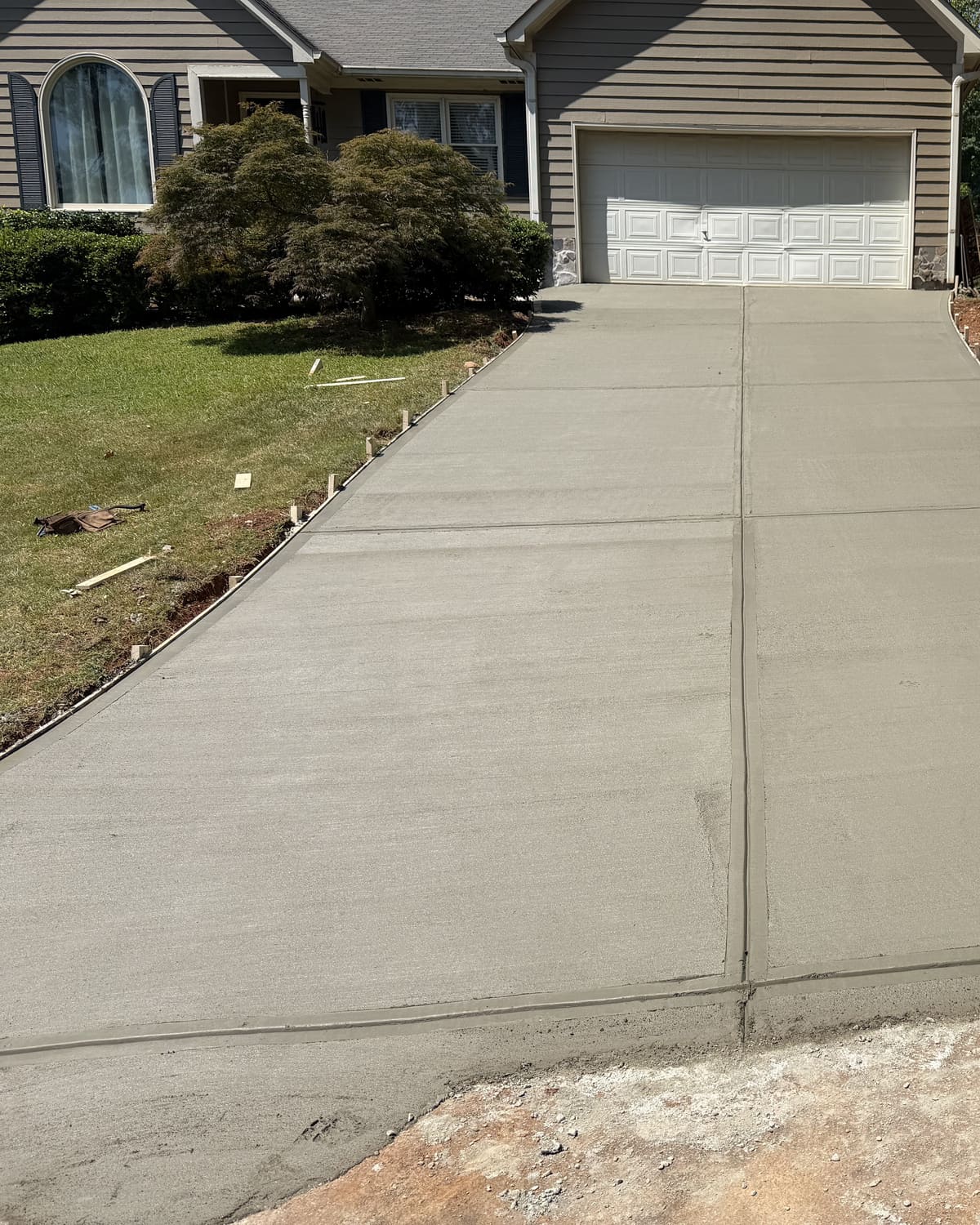 Fresh driveway with a center joint running up to a two-car garage on a gray-sided house