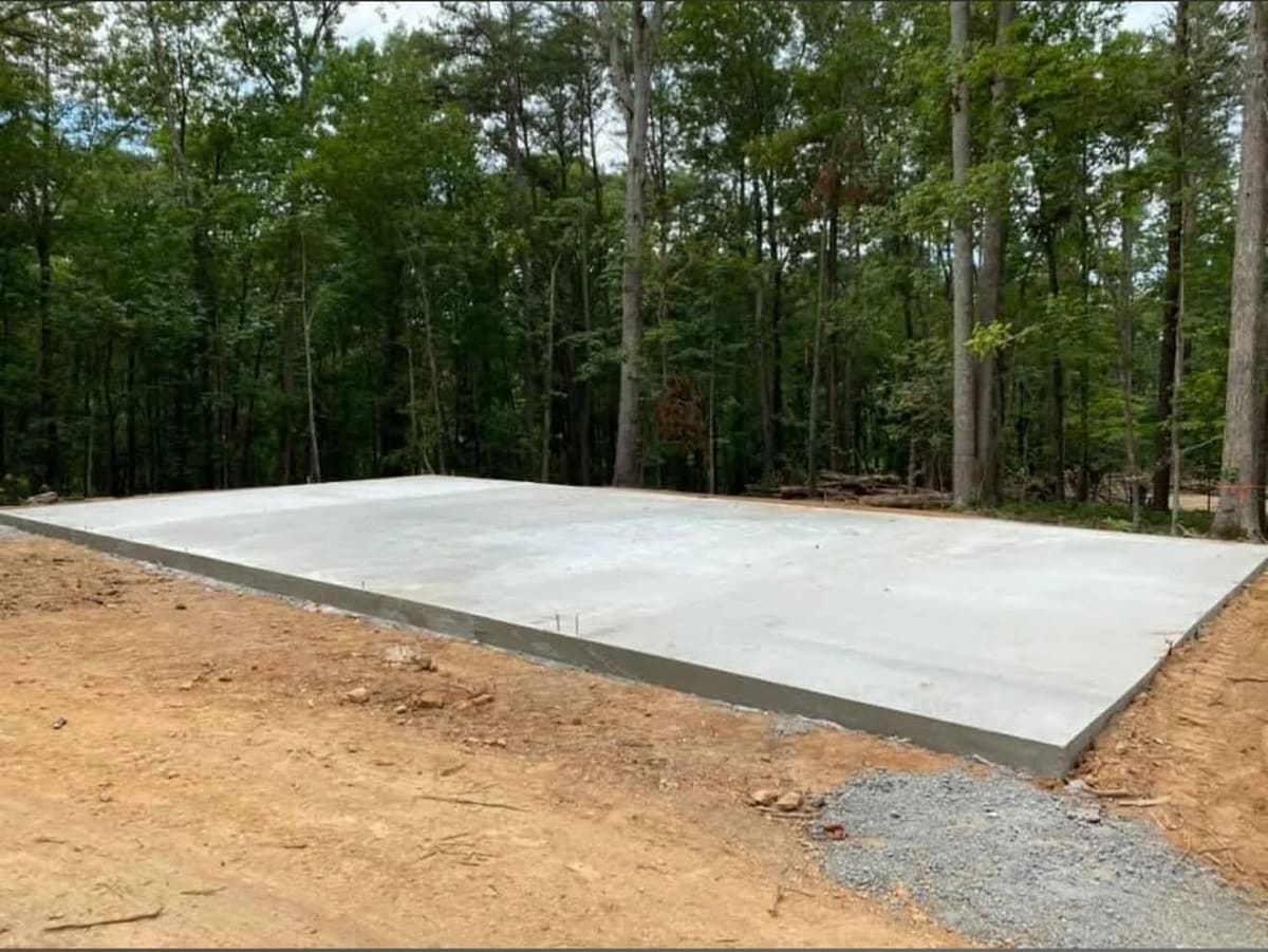 Cured pad at the edge of hardwood woods, a patch of gravel in the foreground