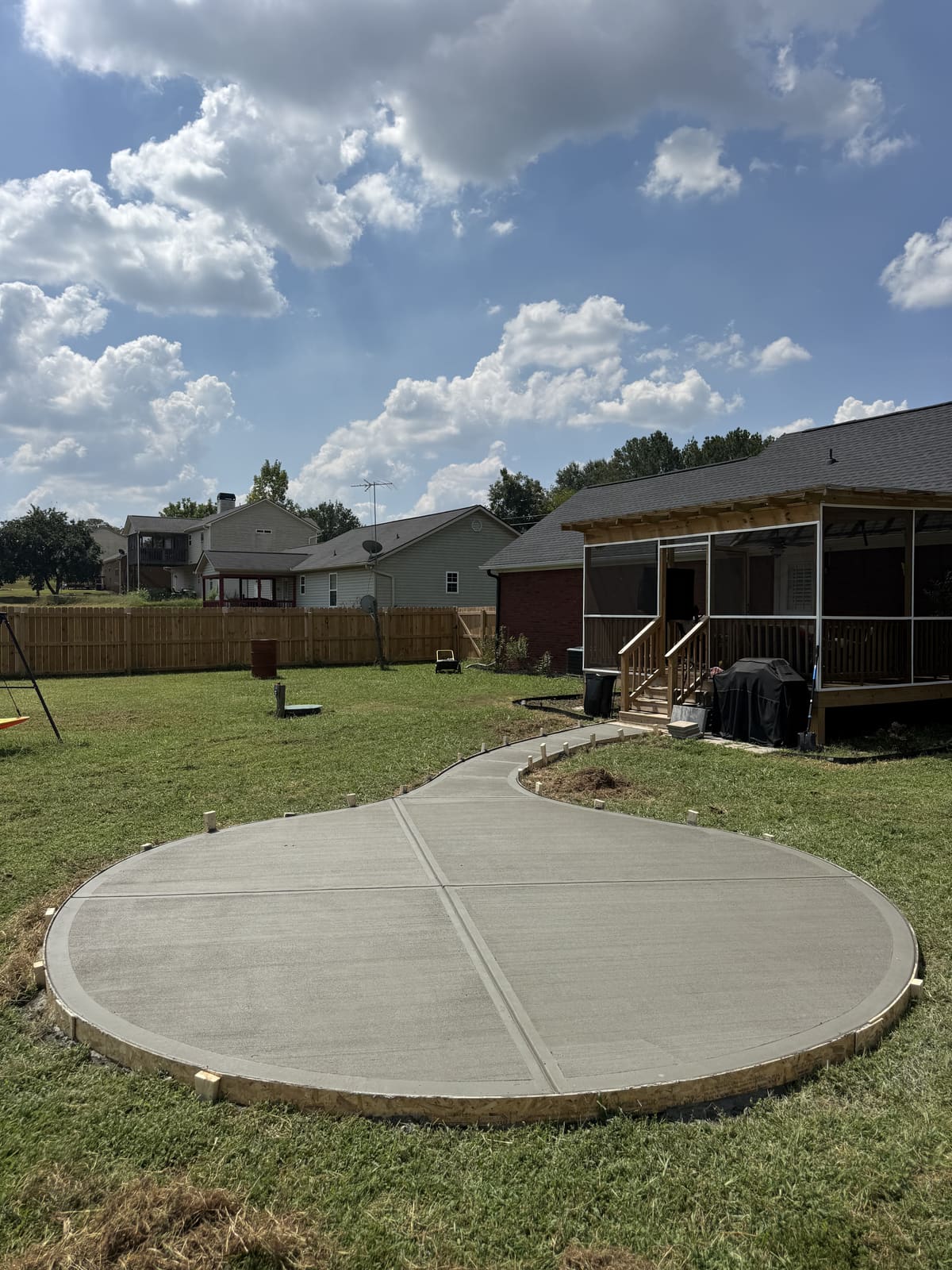 Fresh round patio slab in curved plywood forms with a winding walkway to a screened porch